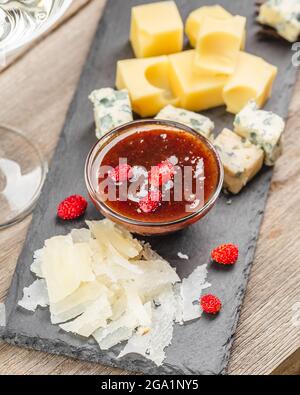 Erdbeermarmelade mit Käse auf einer Schieferplatte. Vorspeisen mit Wein Stockfoto