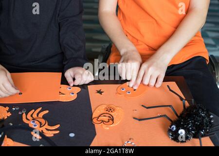 Halloween Kinder Handwerk Vorbereitungen. Kleine Kinder, die zu Hause oder in der Schule basteln, tragen schwarze und orangefarbene Kleidung für die Feiertagsparty Stockfoto