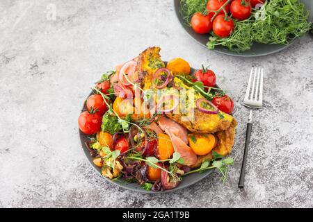 Omelette mit geschmortem Gemüse und Lachs, Tomaten mit Zwiebeln, Brokkoli und rotem Fisch mit Erbsen-Microgreens, leckeres herzhaftes Frühstück Stockfoto