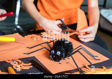 Halloween Kinder Handwerk Vorbereitungen. Kleines Kind, das zu Hause herbstliche Bastelarbeiten macht. Halloween Kinder Party Konzept. Stockfoto