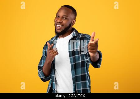 Positiver Schwarzer Bartmann, Der Mit Den Fingern Auf Die Kamera Zeigt, Gelber Hintergrund Stockfoto