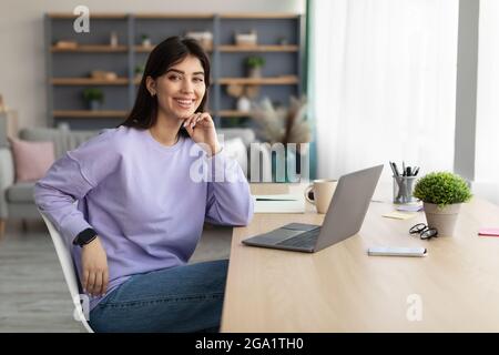 Porträt einer lächelnden jungen Frau, die am Schreibtisch sitzt Stockfoto