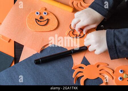 Kleines Kind, das im Herbst zu Hause, in der Schule oder im Kindergarten bastelt. Halloween Kinderparty und diy-Konzept. Stockfoto