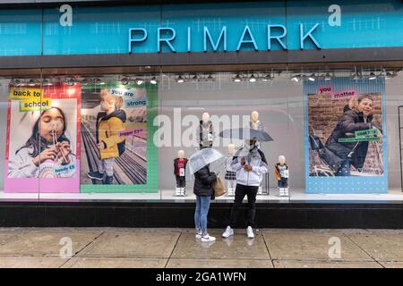 Bei den starken Regenschauern im Juli 2021 in London, England, Großbritannien, stehen die Käufer vor einer Filiale von „Primark“ in der Oxford Street unter Regenschirmen Stockfoto