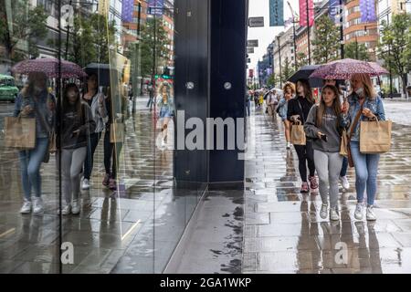 Touristen, die während eines der nasssten Juli-Shootings einkaufen, die je mit den hohen Regenschauern in der Geschichte aufgezeichnet wurden, Oxford Street, London, Großbritannien Stockfoto