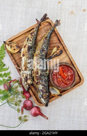 Gegrillte Makrele und Gemüse auf einer Holzplatte. Gegrillter Fisch. Gebratener Fisch, gebackenes Gemüse und Sauce. Stillleben. Draufsicht. Speicherplatz kopieren Stockfoto