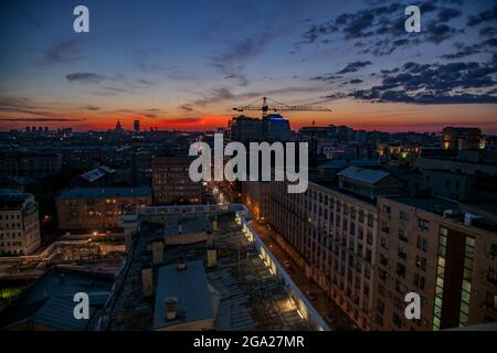 Roter Sonnenuntergang mit Wolken in der Stadt. Bau des Gebäudes mit Kran im Hintergrund. Moskau. Russland. Stockfoto