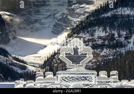 Canadian Maple Leaf Ice Sculpture mit einem Hintergrund eines schneebedeckten Berges im Banff National Park; Lake Louise, Alberta, Kanada Stockfoto