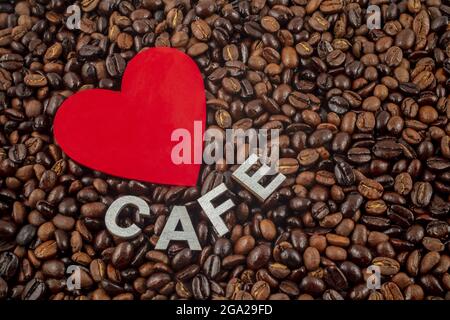 Hintergrund von gerösteten Kaffeebohnen mit einem roten herzförmigen Ausschnitt und dem Wort Cafe auf der Oberseite, ein Traum für Kaffeeliebhaber; Studio Stockfoto