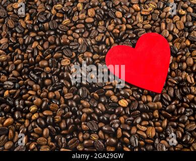 Hintergrund von gerösteten Kaffeebohnen mit einem roten herzförmigen Ausschnitt oben, ein Traum für Kaffeeliebhaber; Studio Stockfoto