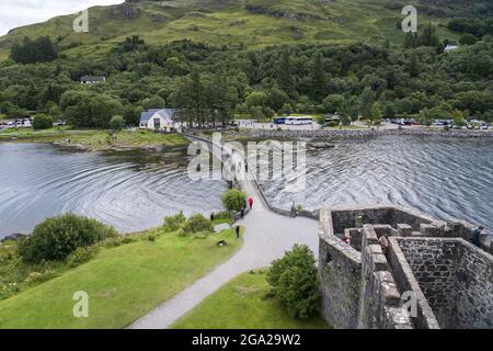 Besucher überqueren die Causeway-Brücke zum Eilean Donan Castle in der Nähe von Kyle of Lochalsh, Schottland; Kyle of Lochalsh, Schottland Stockfoto