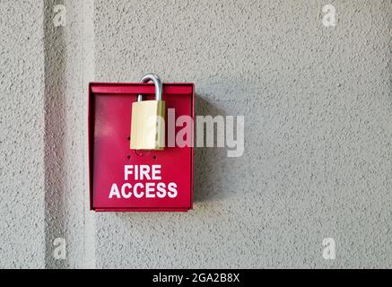 Rote Feuerschutzbox mit Vorhängeschloss an einer einfachen strukturierten Wand mit Platz für Kopien. Stockfoto