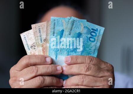 Mann, der echte brasilianische Geldscheine hält Stockfoto