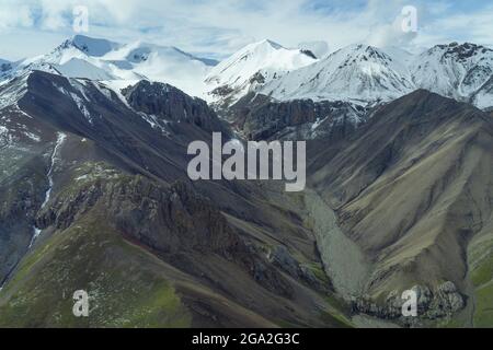 Luftaufnahme der Hänge des alten Sedimentgesteins und vulkanischen Gesteins mit schneebedeckten Berggipfeln am Horizont, im traditionellen Territorium... Stockfoto