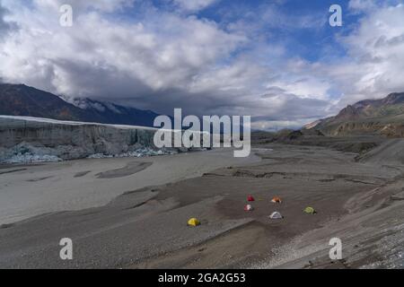 Eine Gruppe von Wanderern schickte ein Basislager mit bunten Zelten vor dem Donjek-Gletscher im Kluane-Nationalpark mit dramatischen Wolkenformationen in der... Stockfoto