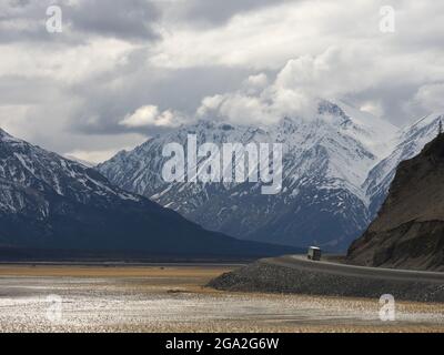 Transport-LKW fahren die Alaska Highway entlang der Seite der ausgetrockneten Teil des Kluane Lake mit riesigen Bergen in der Ferne, in der Trad... Stockfoto