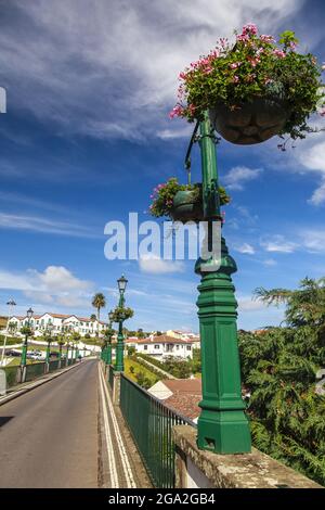 Lampenpfosten gefüllt mit blühenden Pflanzgefäßen säumen die Straße und die historische Brücke in der malerischen Stadt Nordeste; Sao Miguel Island, Azoren Stockfoto