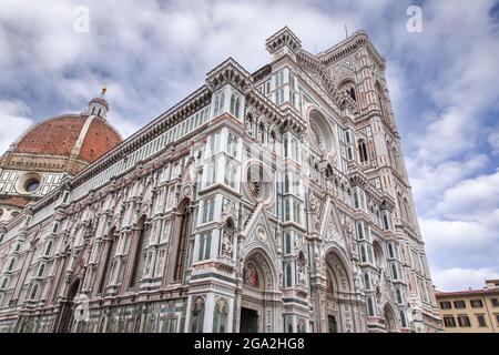 Der berühmte Il Duomo di Firenzano (Kathedrale von Florenz) ist eine hoch dekorierte gotische Struktur aus grünem, weißem und rosafarbenem Marmor an einem wolkenblauen Himmel Stockfoto