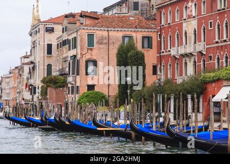 Überdachte Gondeln, die am Kanal vor alten Steingebäuden festgemacht sind; Venedig, Venedig, Italien Stockfoto