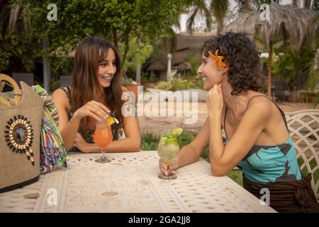 Zwei weibliche Reisende, die draußen an einem Tisch sitzen und Cocktails auf der Gabus Game Ranch trinken; Otavi, Otjozondjupa, Namibia Stockfoto