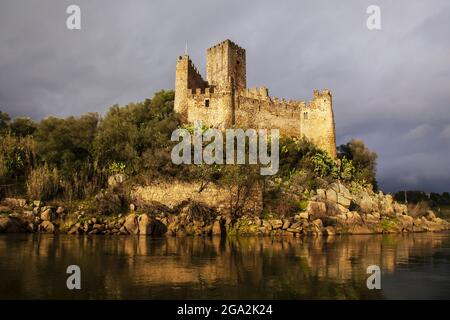 Warmes Sonnenlicht reflektiert den historischen Castlo de Almourol auf der Insel Almourol im Fluss Tejo mit einem grauen Himmel Stockfoto