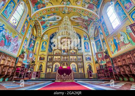 Prachtvolles Interieur aus dem 19. Jahrhundert, die orthodoxe Kathedrale von Zagreb mit ihrem großen Kronleuchter, der über dem Altar hängt, und ihrer farbenfrohen Freskenfarbe... Stockfoto