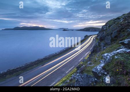 Ein Autoscheinwerfer beleuchtet die schmale Straße nach Slea Head auf der Dingle-Halbinsel; County Kerry, Irland Stockfoto