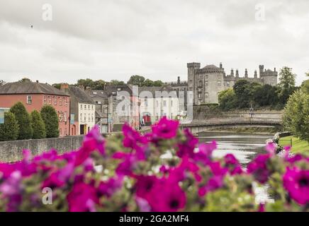 Lila Gartenblumen vor der John's Bridge und dem Fluss Nore, der durch die Stadt Kilkenny mit ihrem Kilkenny Castle aus dem 12.. Jahrhundert... Stockfoto