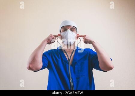 Junger Arzt Porträt in blauen Chirurgen Anzug und schützende Atmung Maske Gläser und Stethoskop auf dem gelben Hintergrund isoliert Stockfoto