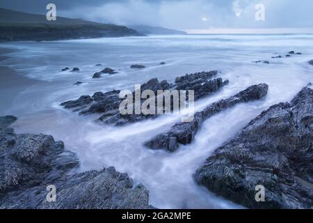 Felsregal am Strand mit stürmischem Himmel an der St. Finian's Bay (The Glen) am Atlantischen Ozean entlang des Skelig Rings; Grafschaft Kerry, Irland Stockfoto