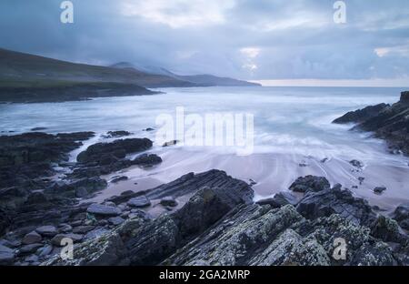 Küstenfelsenschelf am Strand mit stürmischem Himmel an der St. Finian's Bay (The Glen) am Atlantischen Ozean entlang des Skelig Rings; Grafschaft Kerry, Irland Stockfoto