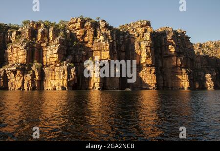 Expeditionsreisende an Bord aufblasbarer Boote erkunden die Sandsteinfelsen mit ihren zerklüfteten Felsklippen entlang des King George River im Kimb... Stockfoto