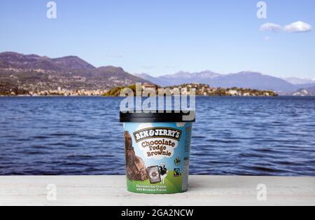 Ben Jerry's Chocolate Fudge Brownie Ice Cream auf weißem Holztisch vor blauem Wasser und Bergen Hintergrund. Stockfoto