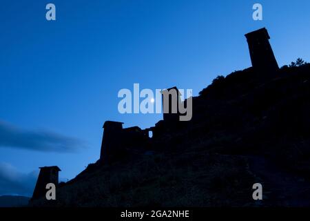 Die Dämmerung fällt über die mittelalterlichen Festungsturmhäuser von Keselo, die den Berghang mit dem Mond, der im Himmel in der Tusheti Nati... Stockfoto