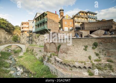 Eine kleine Bogenbrücke über den Fluss Tsavkisi-Tskali mit Liebesschlössern, die an den Geländern vor den alten Gebäuden an den Klippen von Legv... Stockfoto