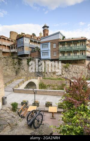 Eine Sitzecke mit einer alten Kanone neben der kleinen Bogenbrücke, die den Tsavkisi-Tskali Fluss überquert, mit Liebesschlössern, die an den Geländern in der... Stockfoto