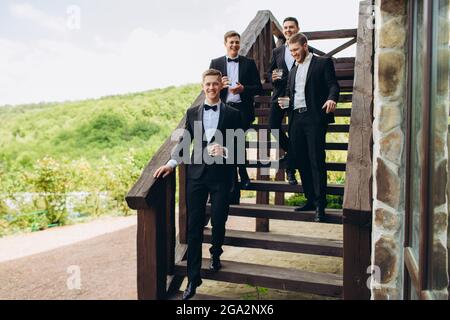 Der Bräutigam und seine Freunde feiern die Hochzeit. Männer in Anzügen. Men Emotionen und Freundschaft. Stockfoto