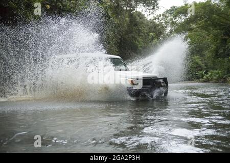Ein Safari-Fahrzeug spritzt durch eine Flussüberquerung im Regenwald Costa Ricas auf der Osa-Halbinsel; Puntarenas, Costa Rica Stockfoto