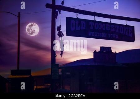 Silhouette eines Skeletts, das von der berühmten, westlichen Stadt Tombstone mit einem Vollmond in einem launischen, violetten Himmel hängt Stockfoto