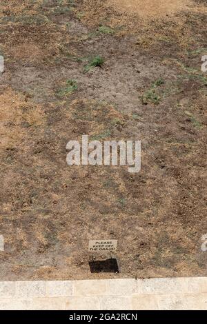 Stark sonnenverbrannter Grasbereich mit Schild mit der Aufschrift „Bitte halten Sie sich vom Gras ab“. Malta. Stockfoto