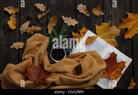 Tasse Kaffee, Laub und Herbstfoto mit offenem Buch. Flatlay Gemütliche Komposition. Kaffee, Bücher und Laub. Warmes und entspanntes Morgenkonzept Stockfoto