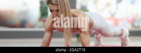 Junge Frau, die auf einer Gymnastikmatte auf einer Planke steht Stockfoto