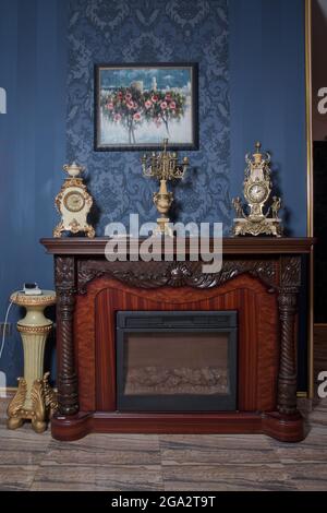 Brauner Kamin. Elektrischer Kamin in einem Holzportal im Zimmer. Kamin isoliert auf blauem Hintergrund. Stockfoto