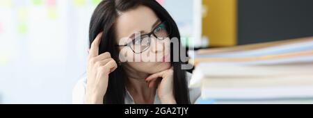 Junge Frau, die sich den Kopf kratzt und viele Ordner ansieht Mit Dokumenten Stockfoto