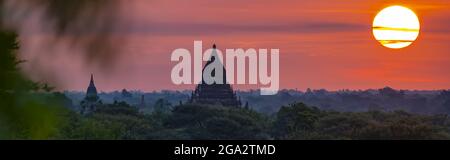 Silhouetten von Pagoden mit der Sonne, die im Morgengrauen über der Ebene von Bagan aufgeht; Bagan, Mandalay, Myanmar (Burma) Stockfoto