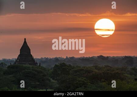 Silhouette einer Pagode mit der Sonne, die im Morgengrauen über der Ebene von Bagan aufgeht; Bagan, Mandalay, Myanmar (Burma) Stockfoto