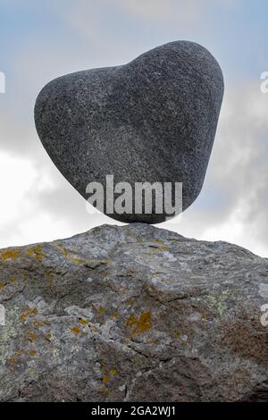 Ein herzförmiger Felsblock, der auf einer Felsoberfläche am Utakleiv-Strand in Lofoten, Norwegen, balanciert ist; Lofoten, Norwegen Stockfoto