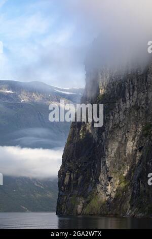 Nahaufnahme der Felswand der steilen Klippen mit nebligen Wolken über dem Seven Sisters Waterfall und spektakulärer Aussicht beim Segeln durch die 15... Stockfoto