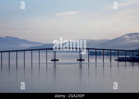 Silhouette der Tromso-Brücke über die Tromsoysundetstraße zwischen Tromsdalen auf dem Festland und der Insel Tromsoya in der Hafenstadt Tromso... Stockfoto