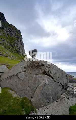 Die dramatische Berg- und Felslandschaft am Utakleiv Beach in Lofoten, Norwegen, mit dem natürlich geformten herzförmigen Felsen, der auf einem ... Stockfoto